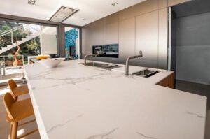 A modern kitchen featuring elegant marble countertops and a large window allowing natural light to fill the space