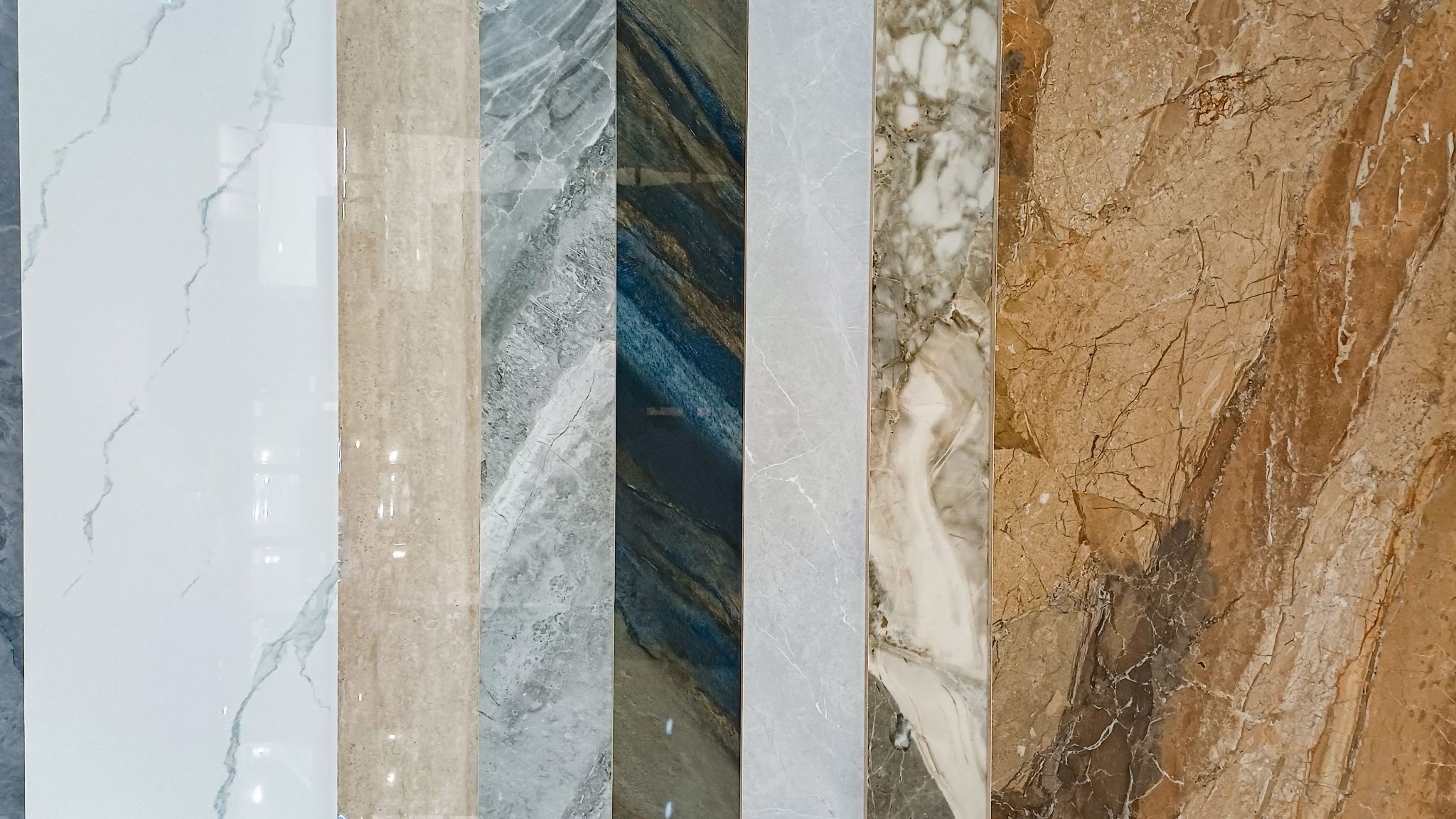 A variety of polished marble and porcelain tile samples arranged side by side showing different colors and veining patterns.