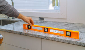 A man uses a level to measure the kitchen countertop.