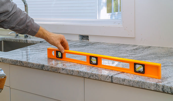 A man uses a level to measure the kitchen countertop.