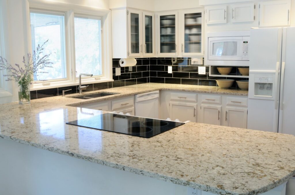 A pristine kitchen with sleek white cabinets and elegant granite counter tops