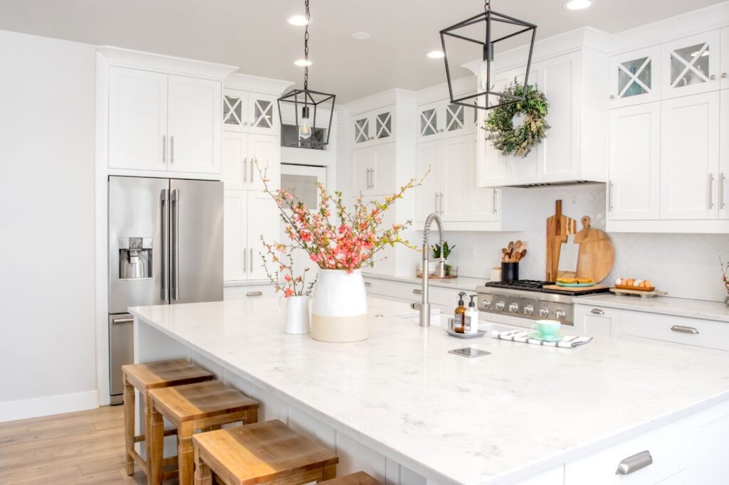White kitchen with center island and wooden stools, perfect for spring cleaning and preparing meals