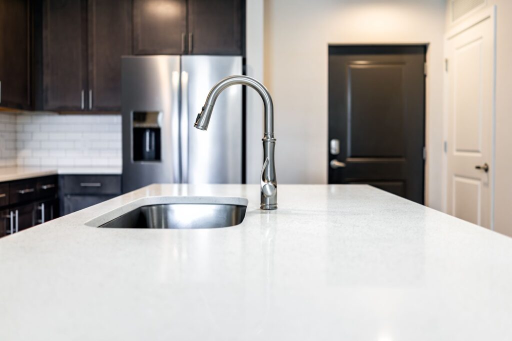 Kitchen with stainless steel sink, black appliances, quartz countertops. Learn how to clean quartz kitchen countertop