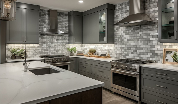 Modern kitchen with grey cabinets and stainless steel appliances, featuring quartz countertops
