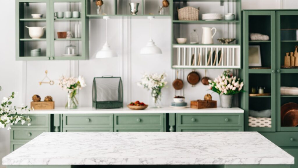 Charming kitchen with green cabinets, marble countertops, flowers, and rustic decor.