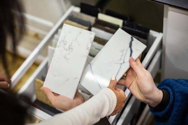A woman displays a piece of marble in her hand highlighting its texture and unique patterns